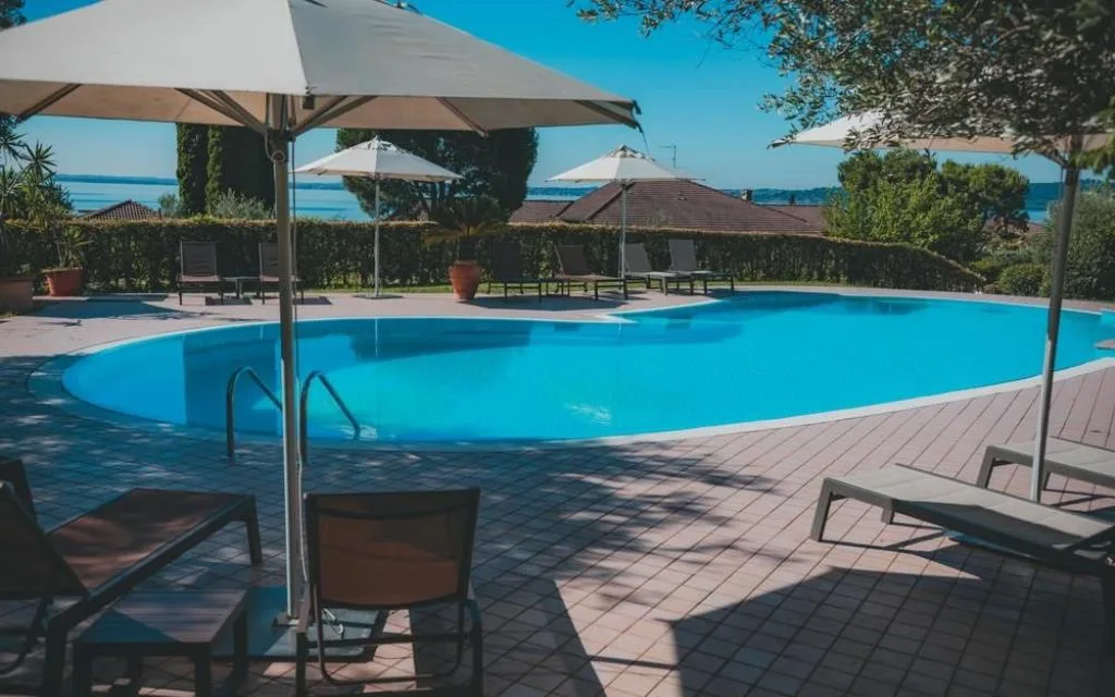 Piscina esterna con ombrelloni e lettini vista lago