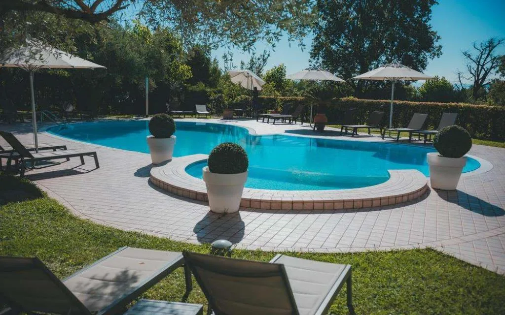 Piscina immersa nel giardino con lettini e ombrelloni