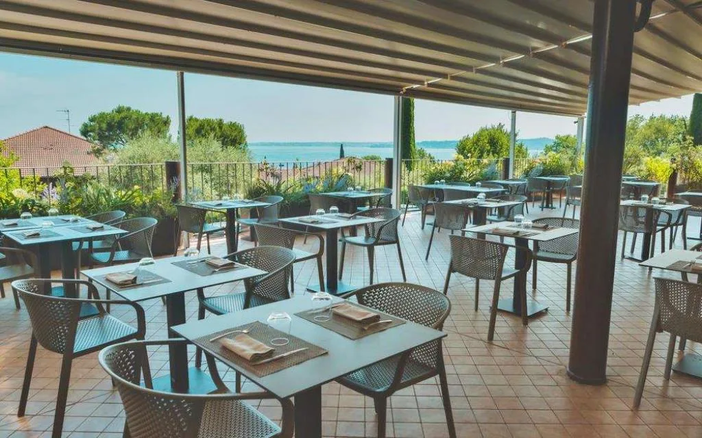 Terrazza del ristorante con tavoli apparecchiati e vista lago