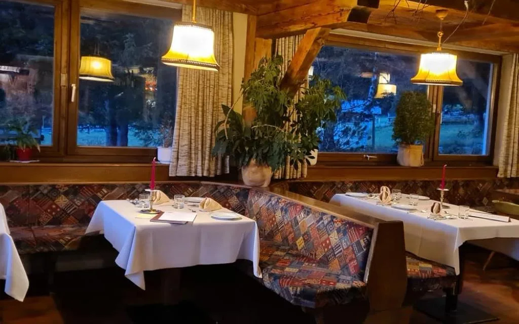 Sala ristorante interna con tavoli apparecchiati, panche colorate e arredi in legno