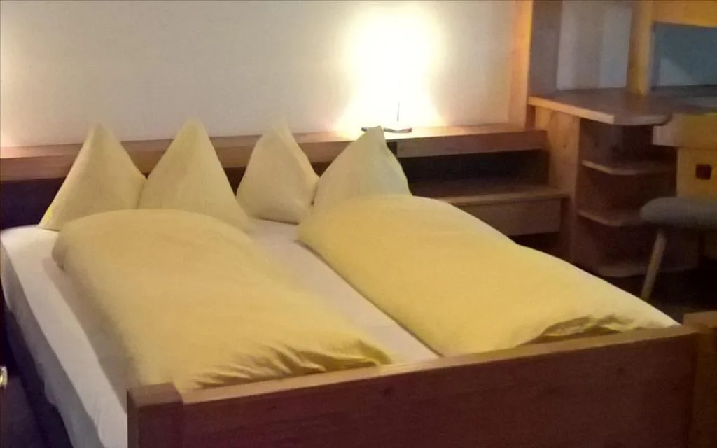 Letto matrimoniale con cuscini gialli, testiera in legno e lampada da comodino