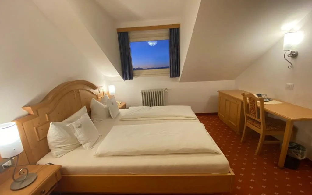 Camera mansardata con letto matrimoniale, scrivania e finestra con vista sulle montagne