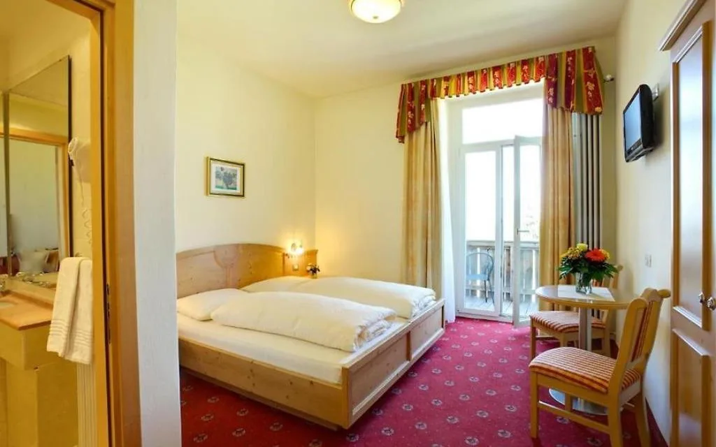 Camera con letto matrimoniale, moquette rossa e porta finestra che dà sul balcone