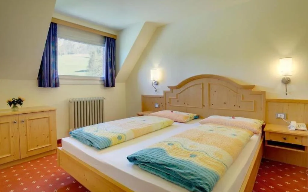 Camera con letto matrimoniale in legno, moquette rossa e finestra con vista sul paesaggio