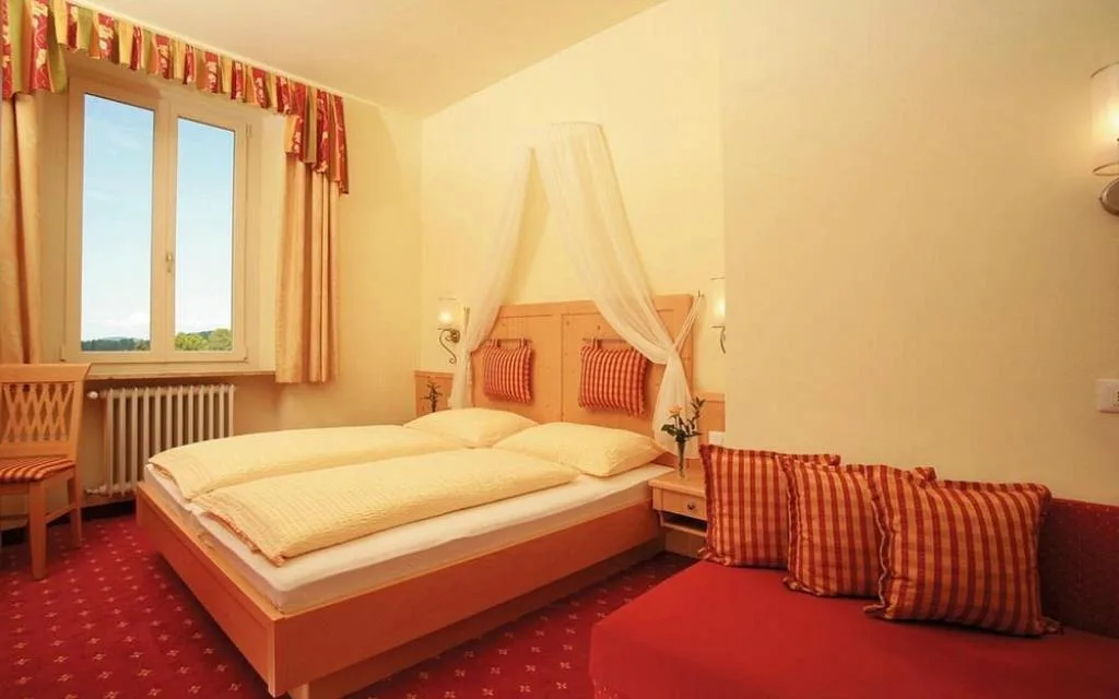 Camera luminosa con letto matrimoniale, baldacchino e divanetto a righe rosse