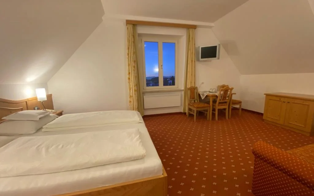 Camera mansardata spaziosa con letto matrimoniale, zona tavolo e vista sulle montagne