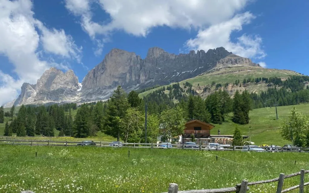 Prato verde estivo con recinzione in legno e Dolomiti maestose sullo sfondo