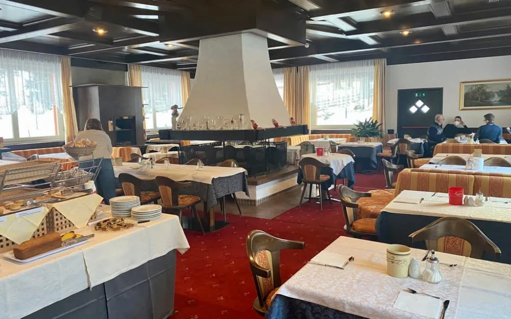 Sala colazione con tavoli apparecchiati, buffet e camino centrale
