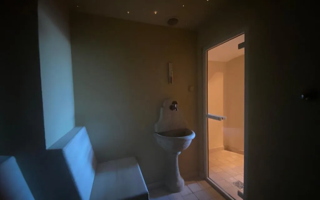 Zona umida della spa con panca, fontanella in pietra e accesso al bagno turco