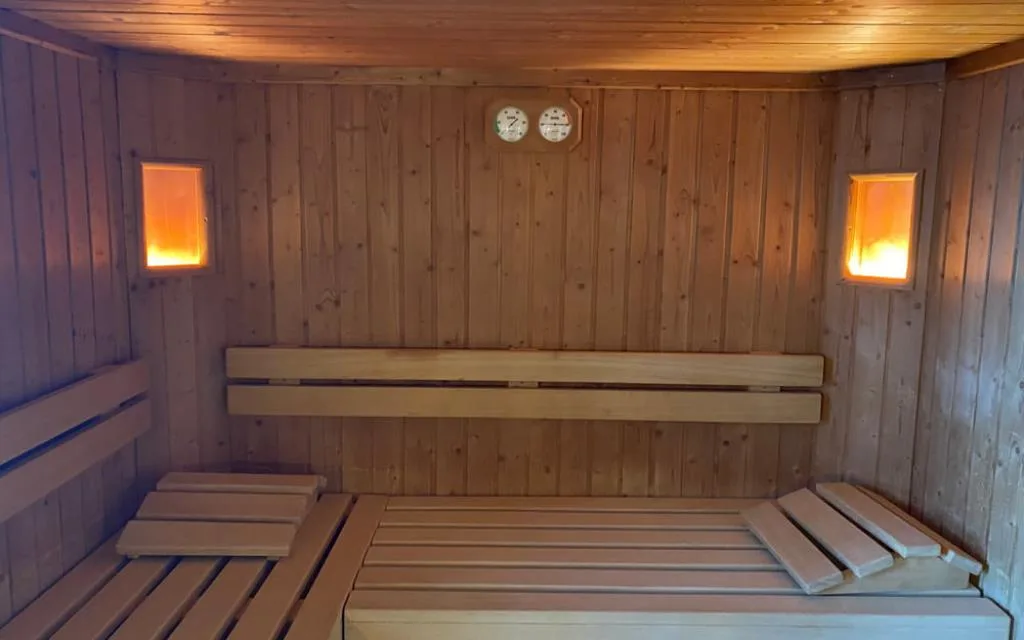 Interno della sauna in legno con panche e termometro a parete