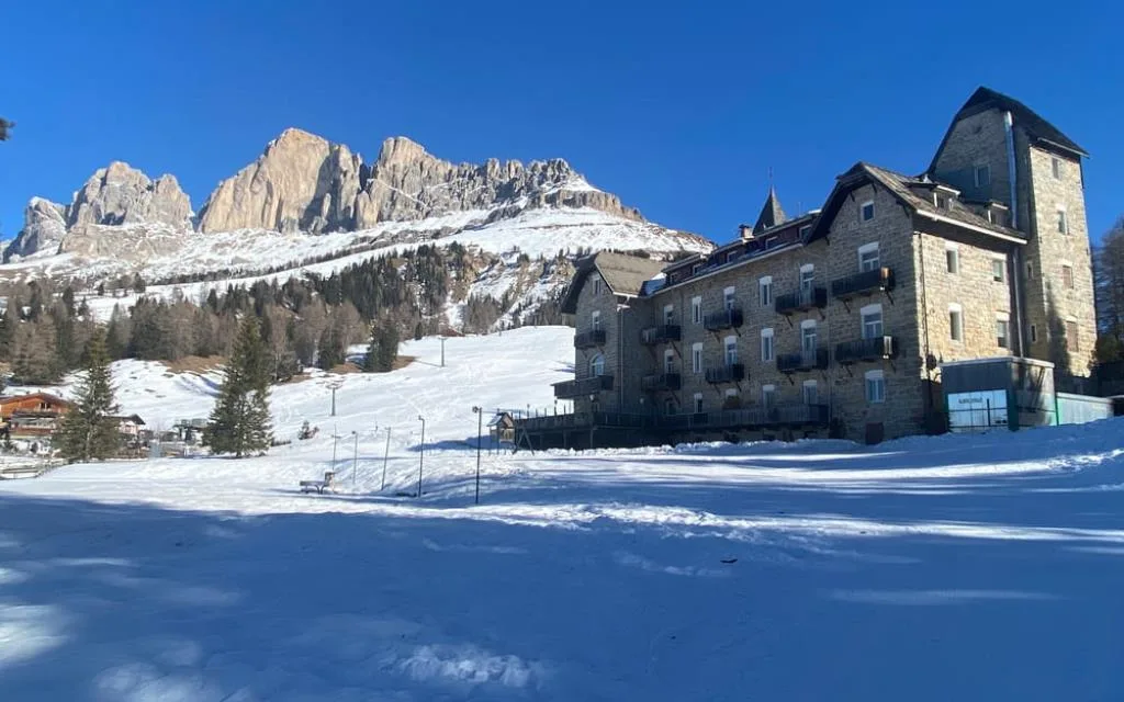 Hotel Castel Latemar in inverno con torretta e Dolomiti innevate sullo sfondo