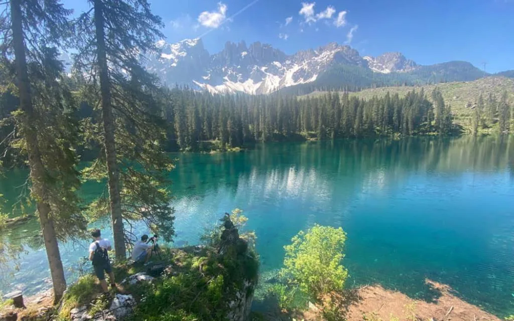 Lago di Carezza dalle acque turchesi con abeti e Dolomiti innevate sullo sfondo