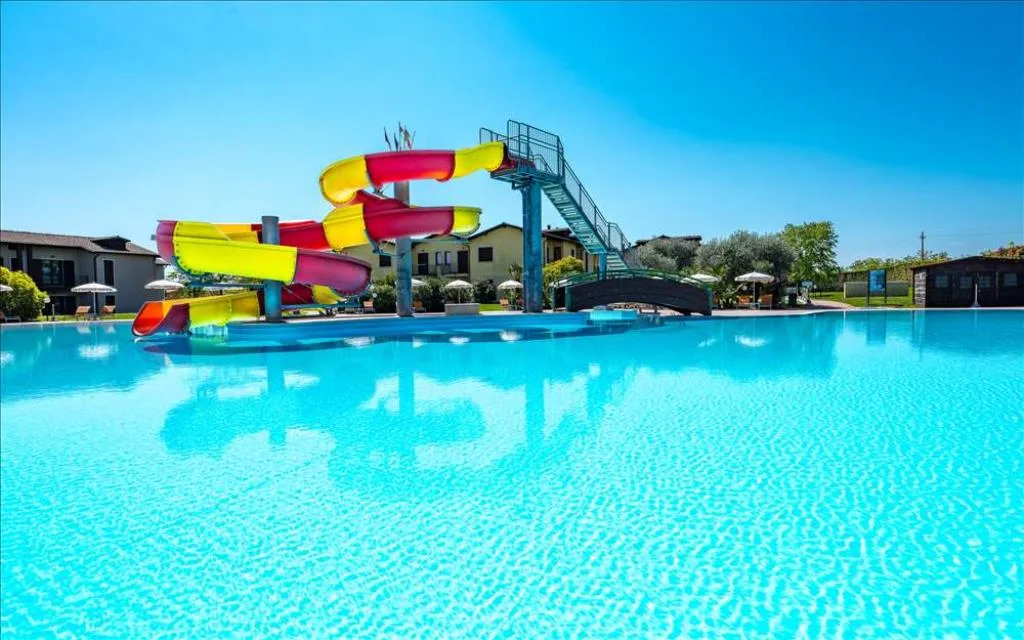 Grande piscina con scivoli d'acqua colorati e ponte, ideale per famiglie