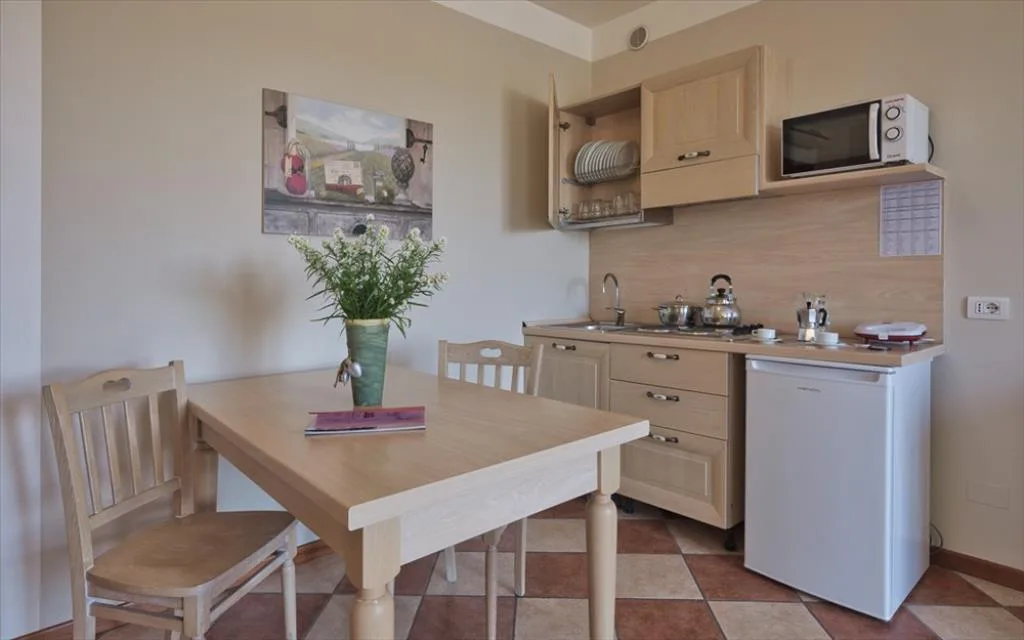 Cucinino attrezzato con tavolo in legno chiaro, microonde e frigorifero
