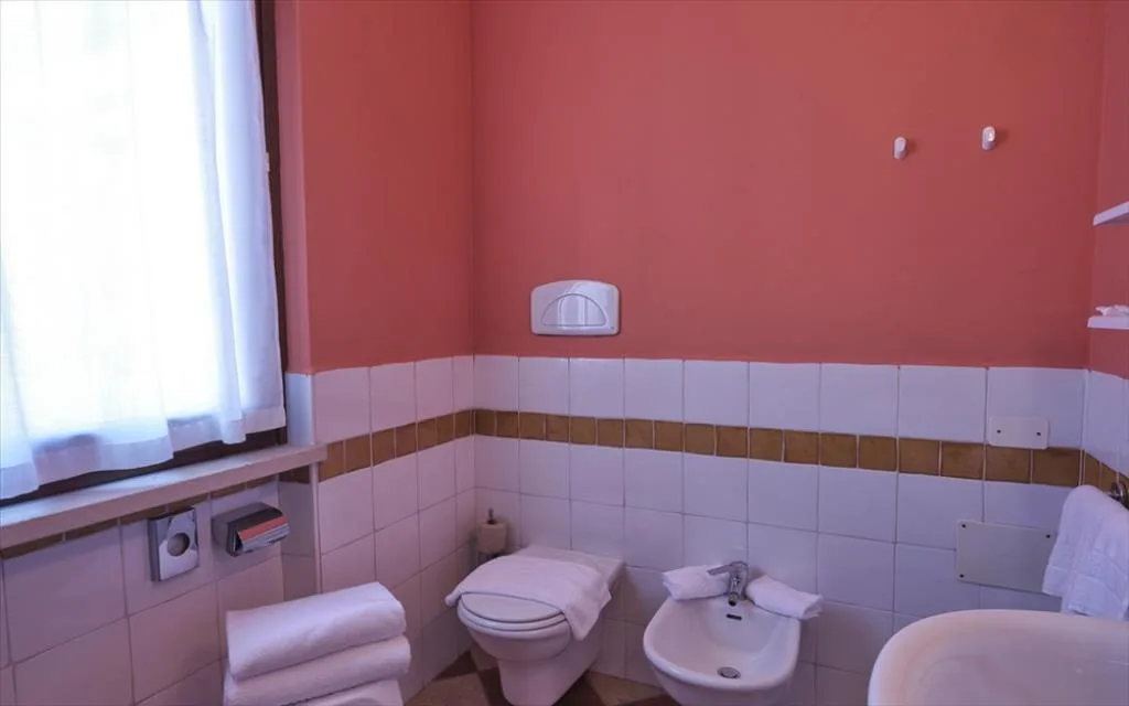 Bagno con pareti color corallo, wc, bidet e piastrelle bianche
