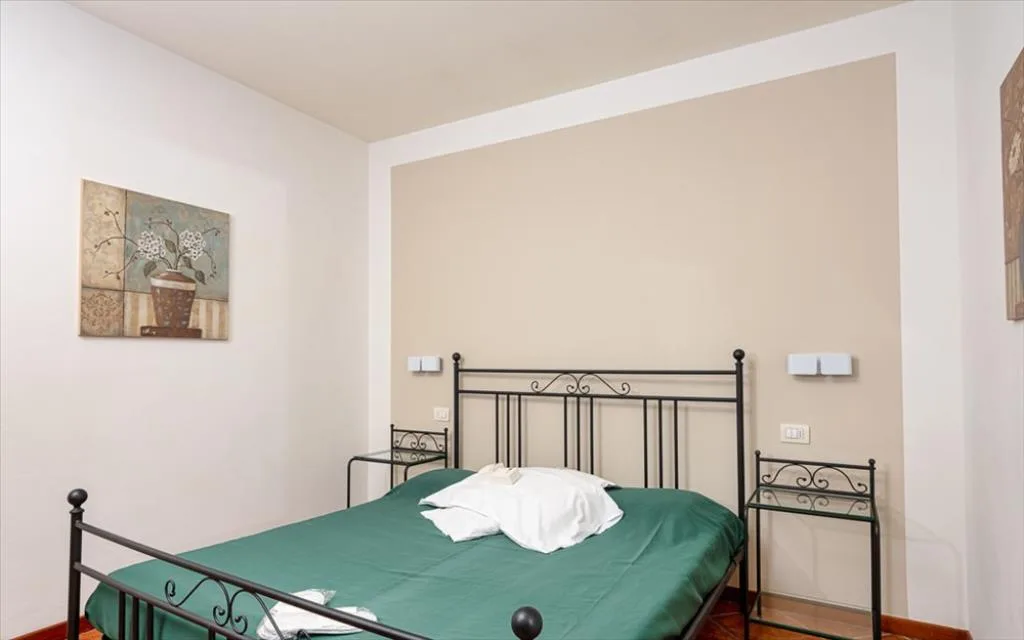 Camera da letto con letto matrimoniale in ferro e copriletto verde