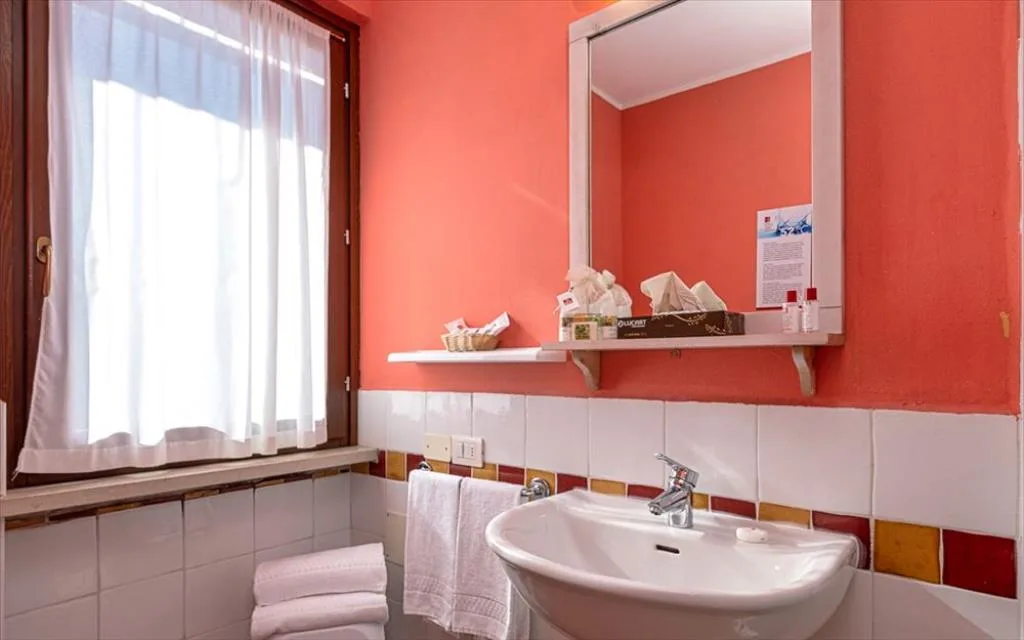 Bagno con pareti color corallo, lavabo e specchio con articoli da toeletta