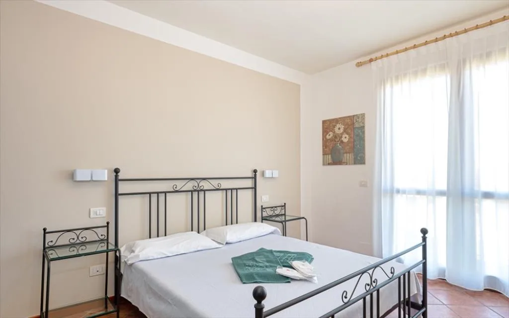 Camera con letto matrimoniale in ferro battuto e finestra luminosa