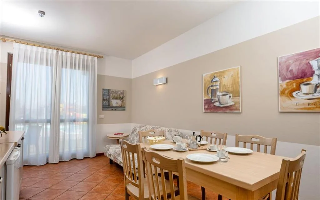 Soggiorno con tavolo da pranzo apparecchiato, divano e quadri alle pareti
