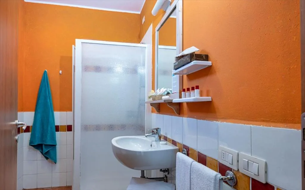 Bagno con pareti arancioni, doccia, lavabo e specchio