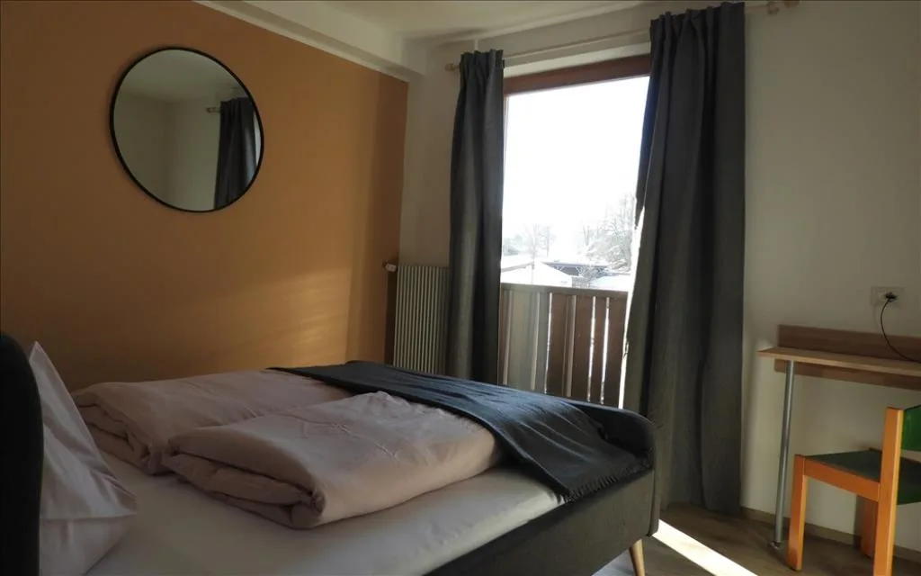 Camera con letto matrimoniale, specchio rotondo, scrivania e balcone