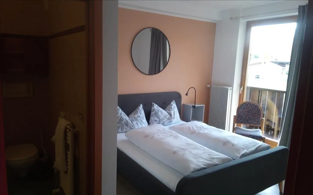 Camera con letto matrimoniale, specchio rotondo e bagno privato attiguo