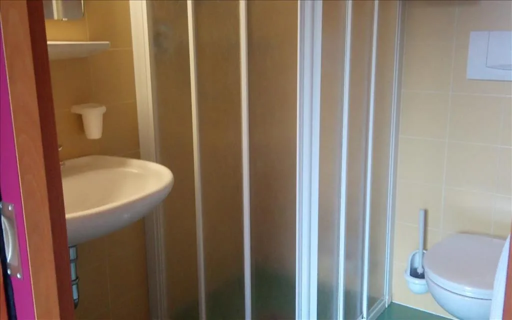 Bagno con doccia, lavabo e servizi igienici con piastrelle beige