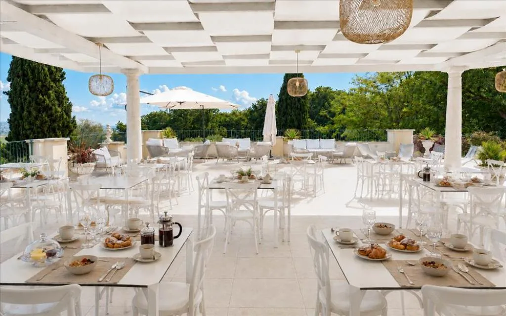 Terrazza ristorante bianca allestita per la colazione con vista sul verde e le colline
