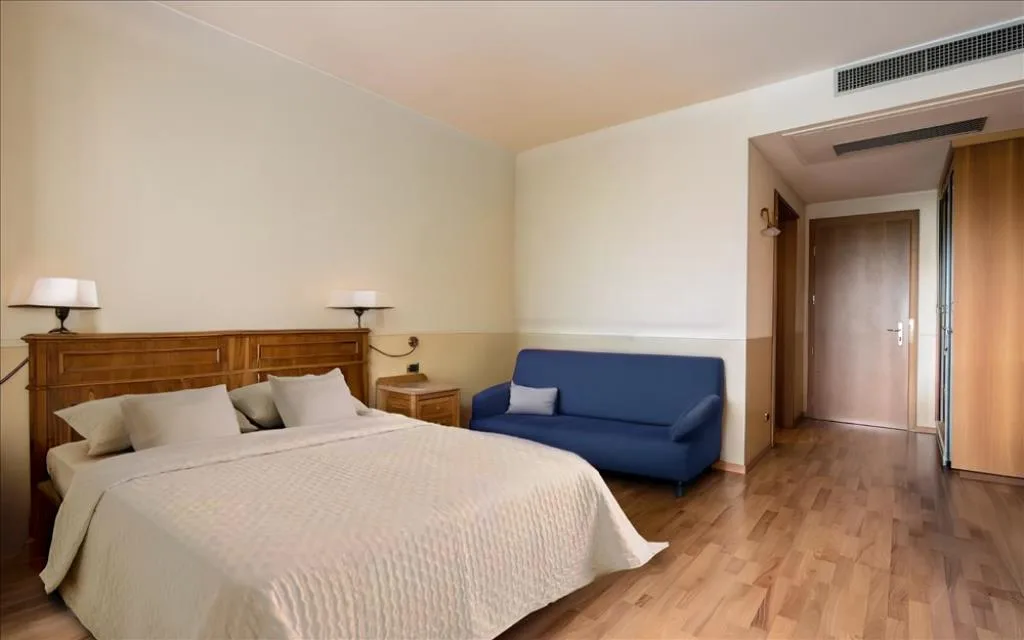 Camera matrimoniale con letto, divano blu e pavimento in parquet