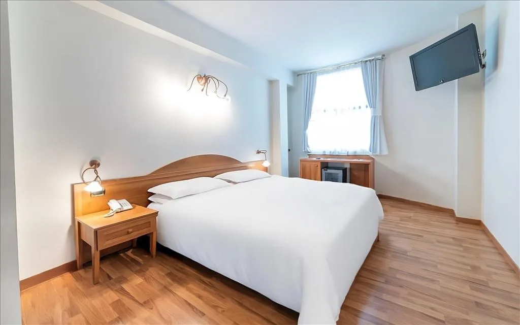 Camera con letto matrimoniale, testiera in legno, TV a parete e finestra