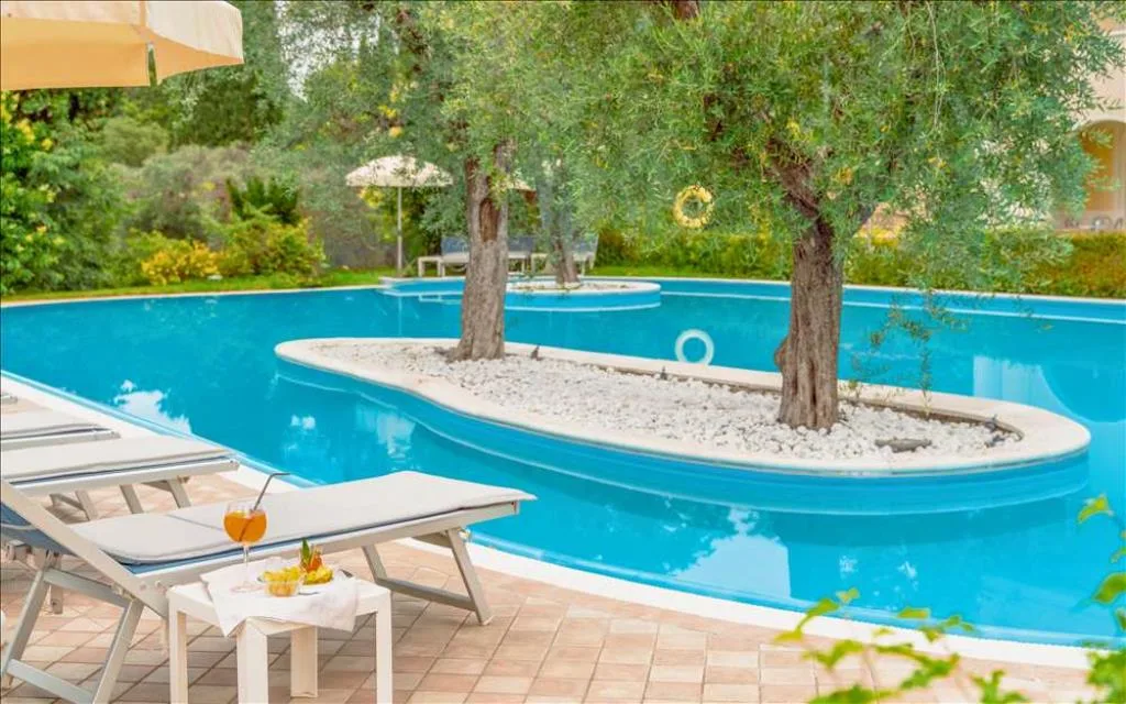 Dettaglio della piscina con ulivi su isole di ciottoli bianchi, lettino e aperitivo