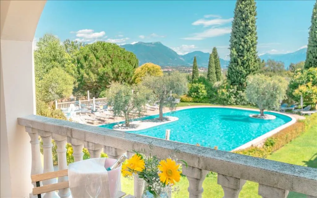 Vista dal balcone sulla piscina, il giardino e le montagne con fiori e spumante