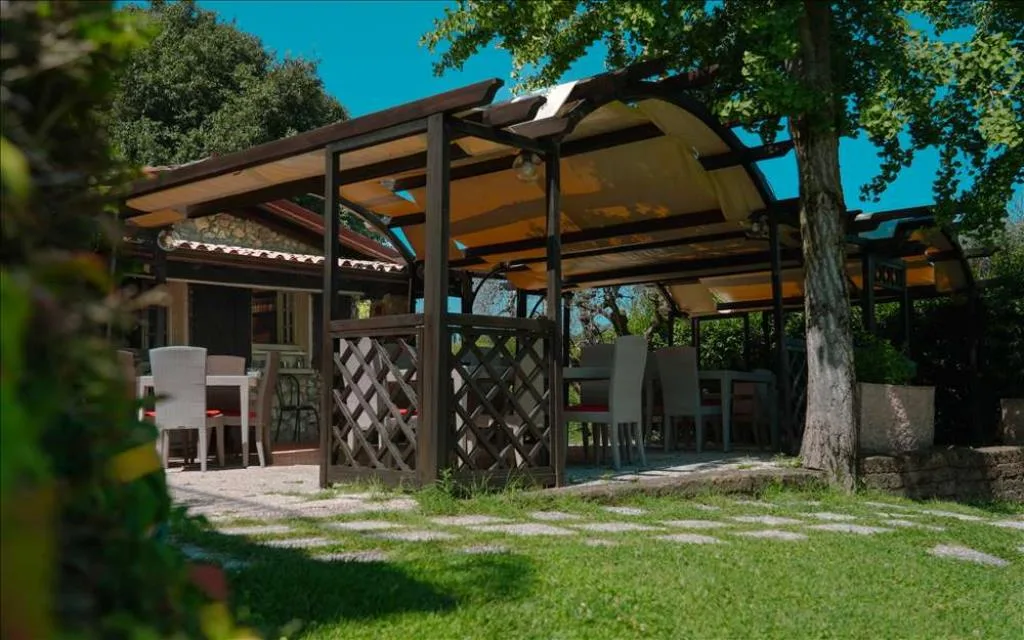 Gazebo esterno con pergolato in legno e tavoli apparecchiati nel giardino