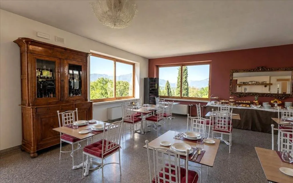 Sala colazione interna con tavoli apparecchiati, buffet e vista sulle montagne