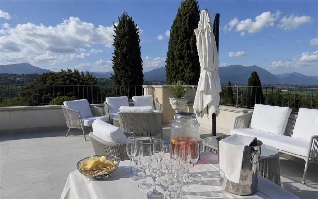 Terrazza panoramica con divani bianchi e tavolo con aperitivo e vista montagne