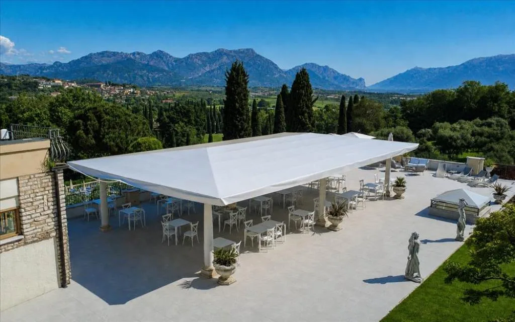 Ampia terrazza coperta con tavoli bianchi e statue con vista sulle montagne
