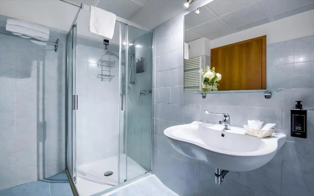 Bagno moderno con doccia in vetro, lavabo bianco e specchio