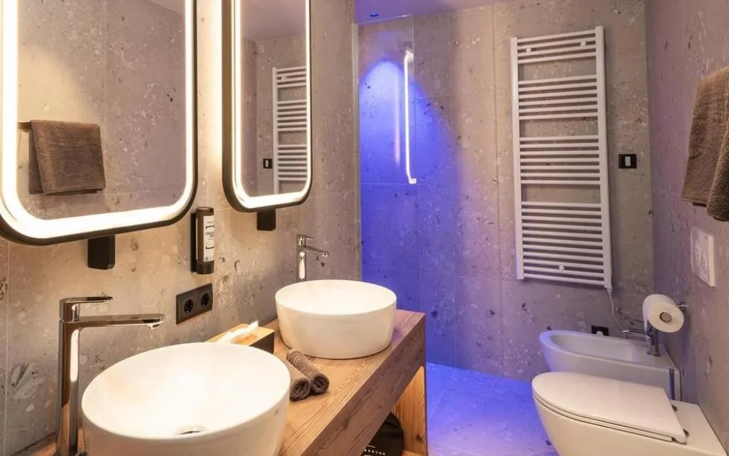 Bagno moderno con doppio lavabo, specchi illuminati e illuminazione blu ambientale