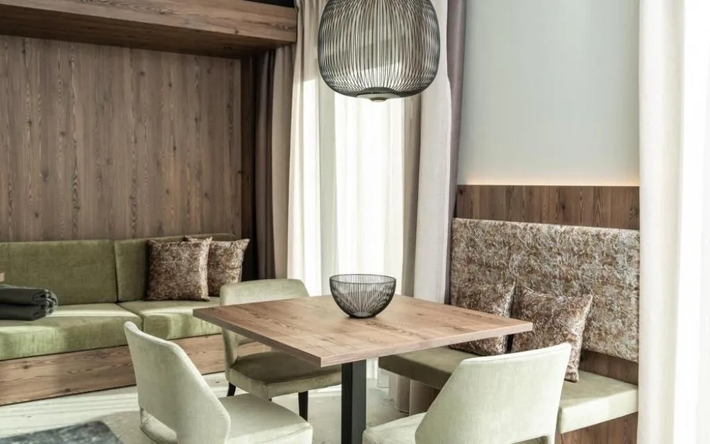 Salottino con divano verde, tavolo in legno e lampada a sospensione decorativa