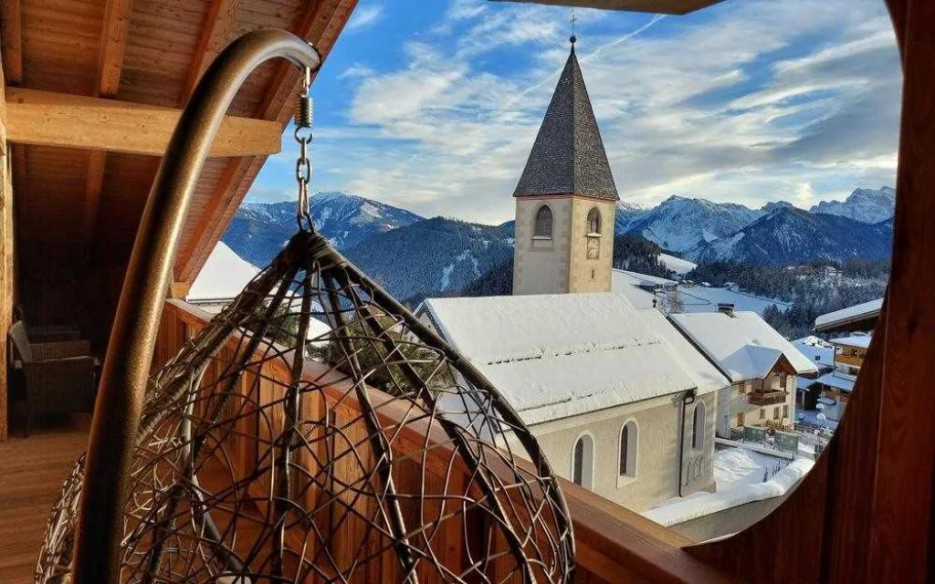 Poltrona sospesa su balcone con vista sul campanile e le montagne innevate