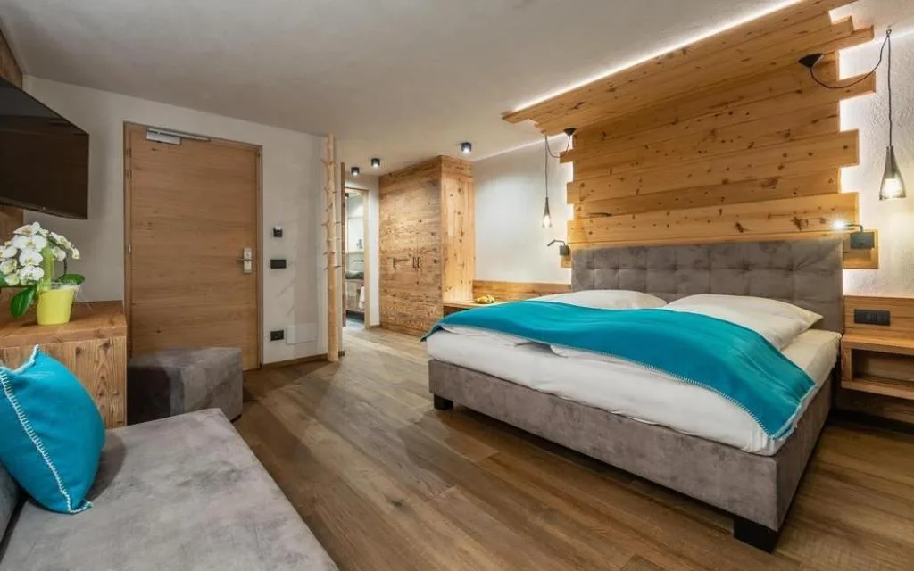 Camera spaziosa con letto matrimoniale, divano e arredi in legno naturale