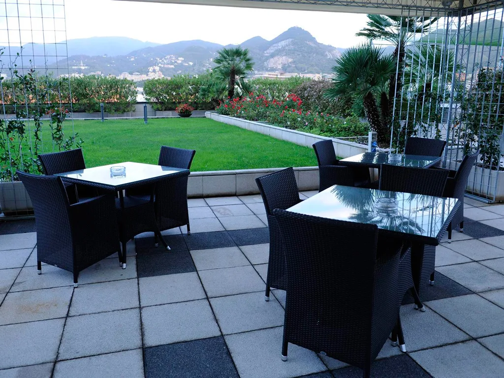 Terrazza panoramica con tavoli e sedie in vimini e vista sulle colline e il giardino
