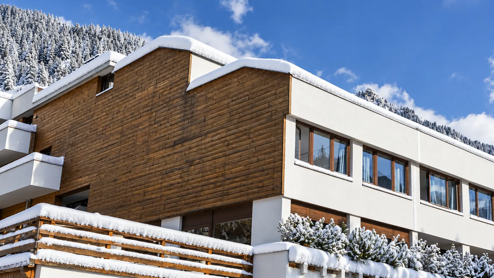 Dettaglio architettonico della facciata in legno e balconi innevati dell'hotel