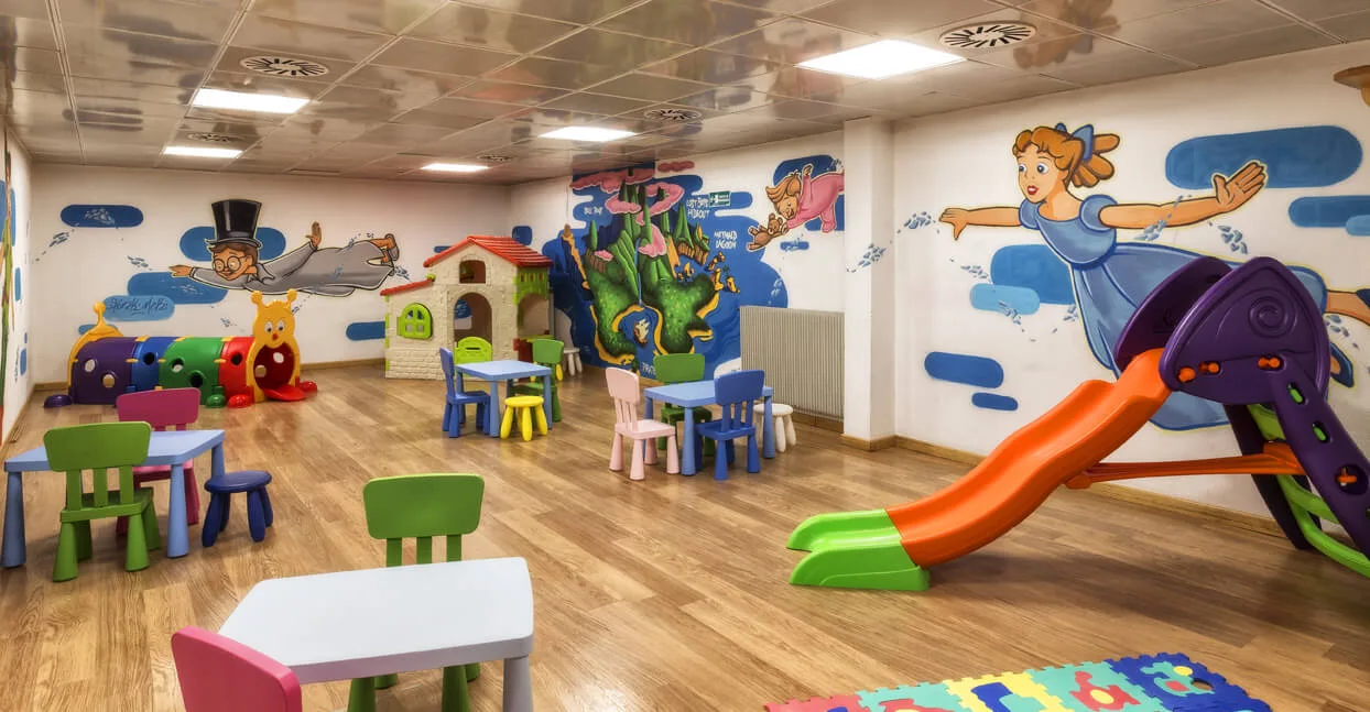 Area giochi per bambini colorata con scivolo, tavolini e murales