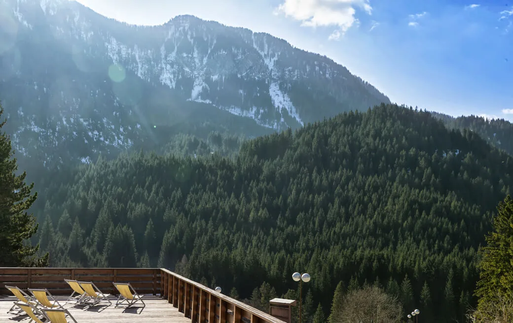 Terrazza panoramica con sdraio affacciata su valle boscosa e montagne