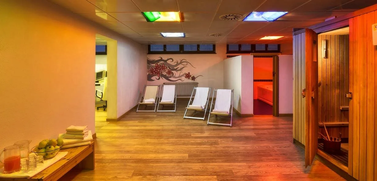 Area relax della spa con lettini, sauna in legno e illuminazione colorata