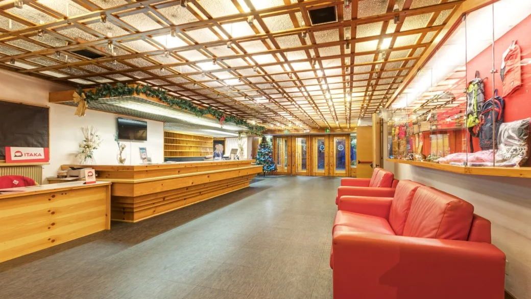Area reception con bancone in legno, divani rossi e albero di Natale