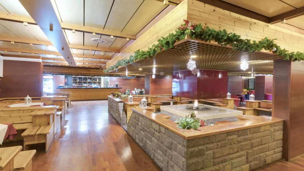 Area lounge bar con focolare centrale in pietra e arredi in legno