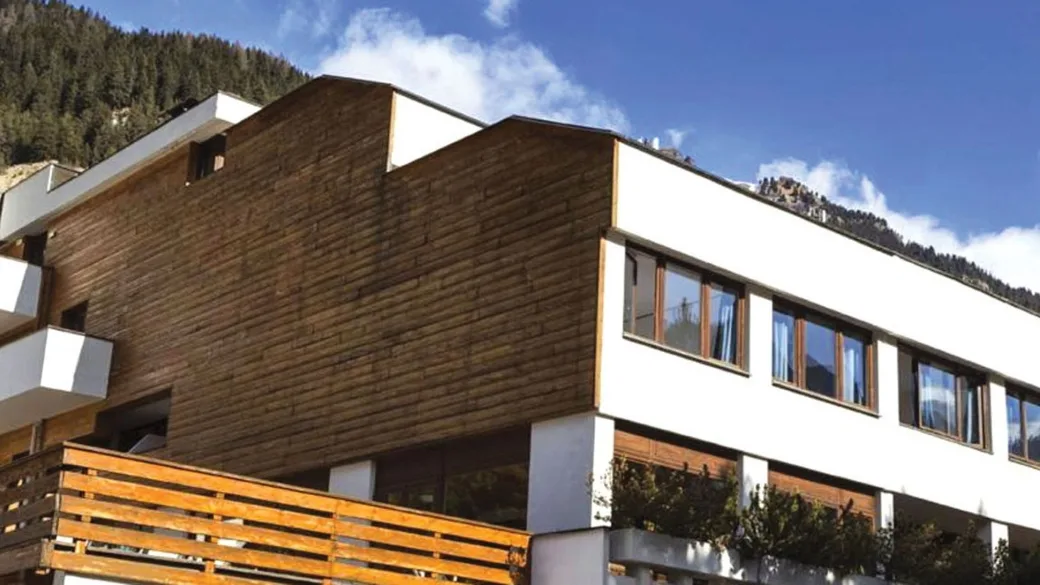 Dettaglio della facciata dell'hotel in legno e intonaco bianco con montagne