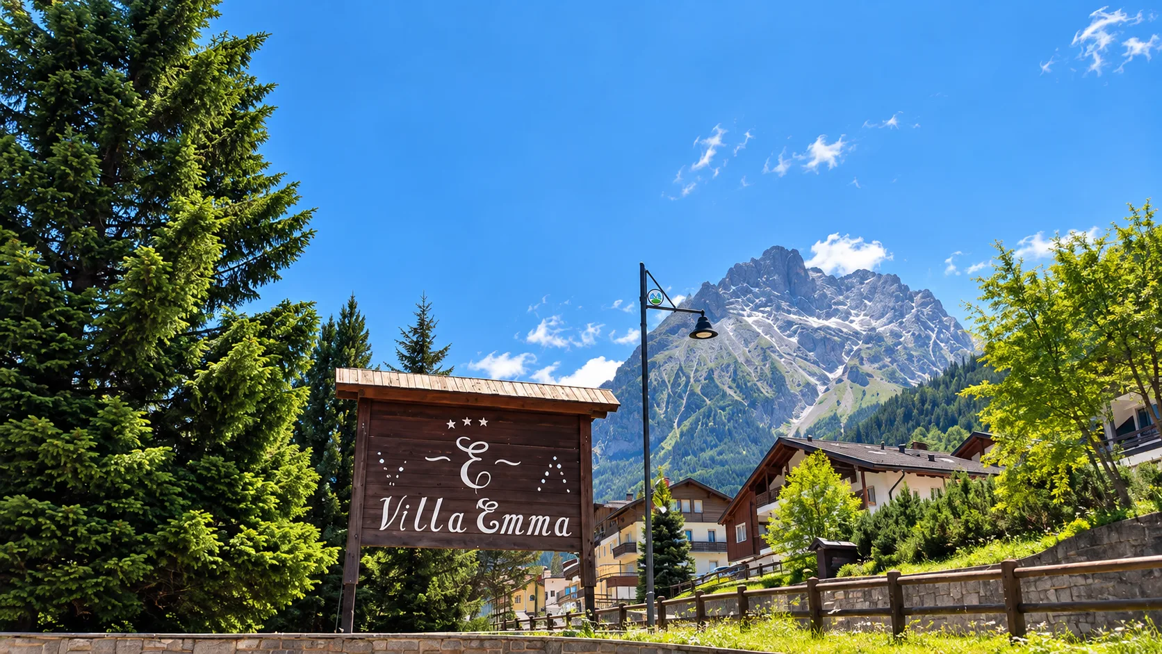 Insegna Villa Emma con vista sulle Dolomiti e vegetazione estiva